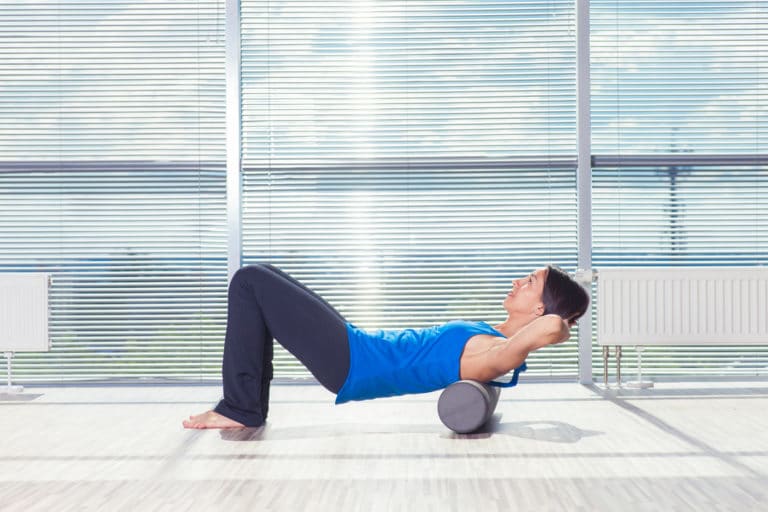 fitness, sport, training and lifestyle concept - woman doing pil | Change Sports Physical Therapy Institute Foam roll on the back